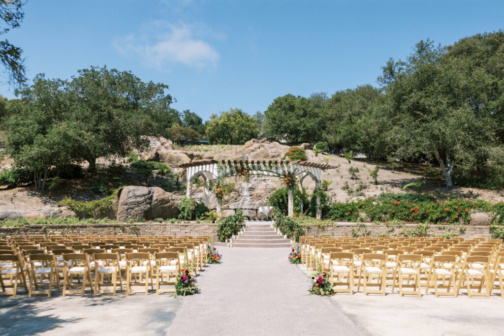 Outdoor garden ceremony space with stone backdrop and floral installations