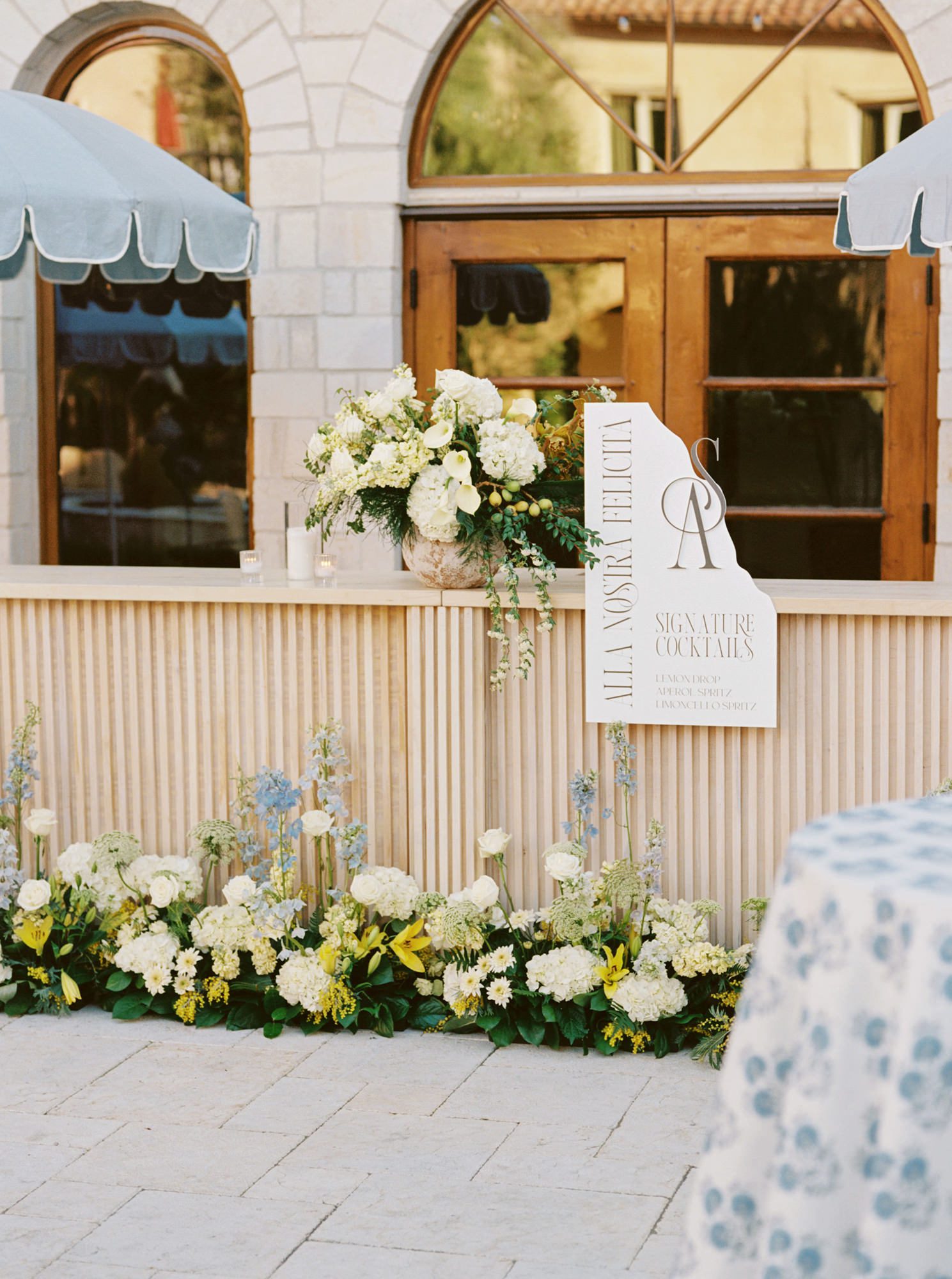 Welcome sign with shoreline die cut and custom monogram displayed at the bar in an Italian-inspired courtyard.