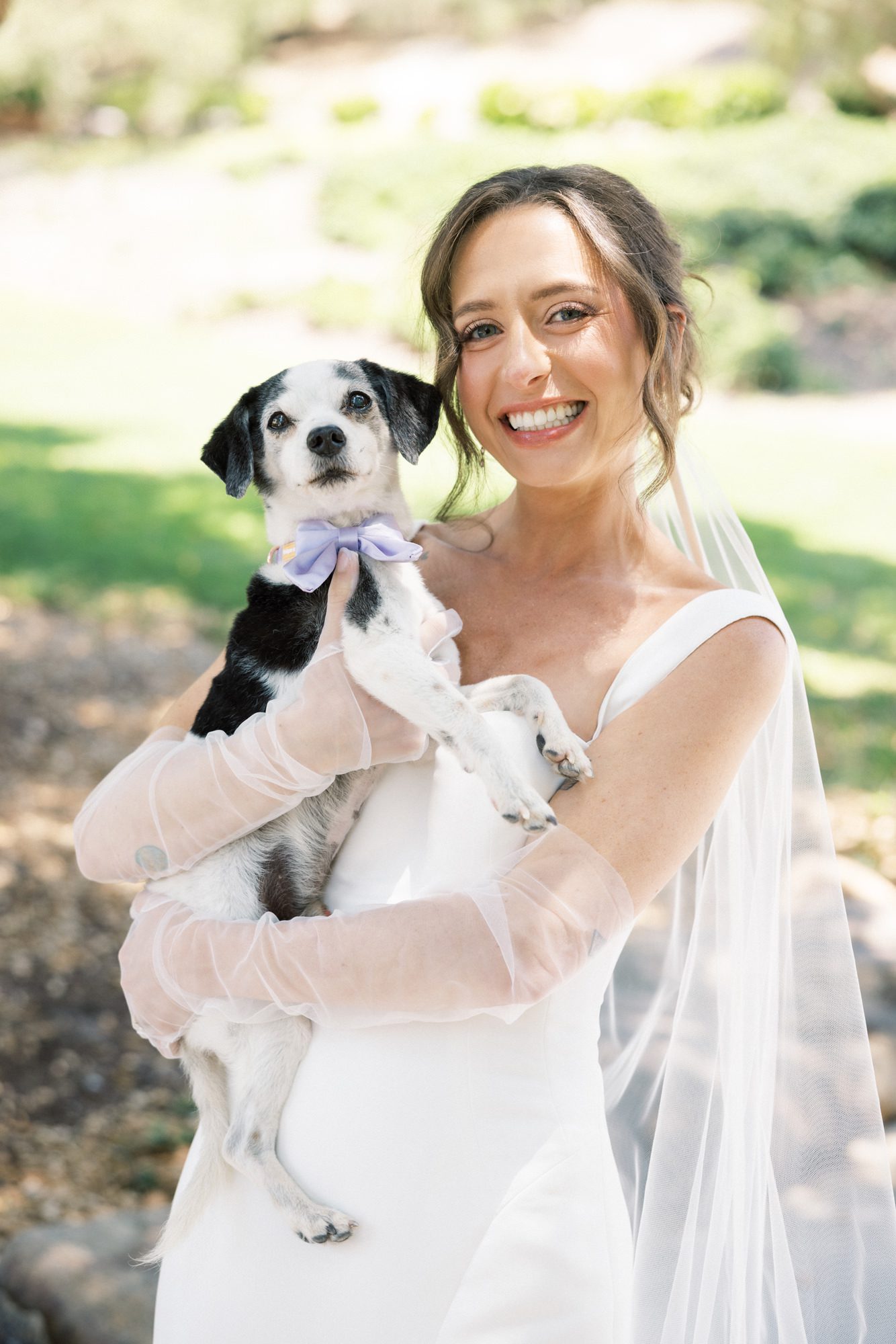 Bride and groom with dog at outdoor wedding venue in garden setting
