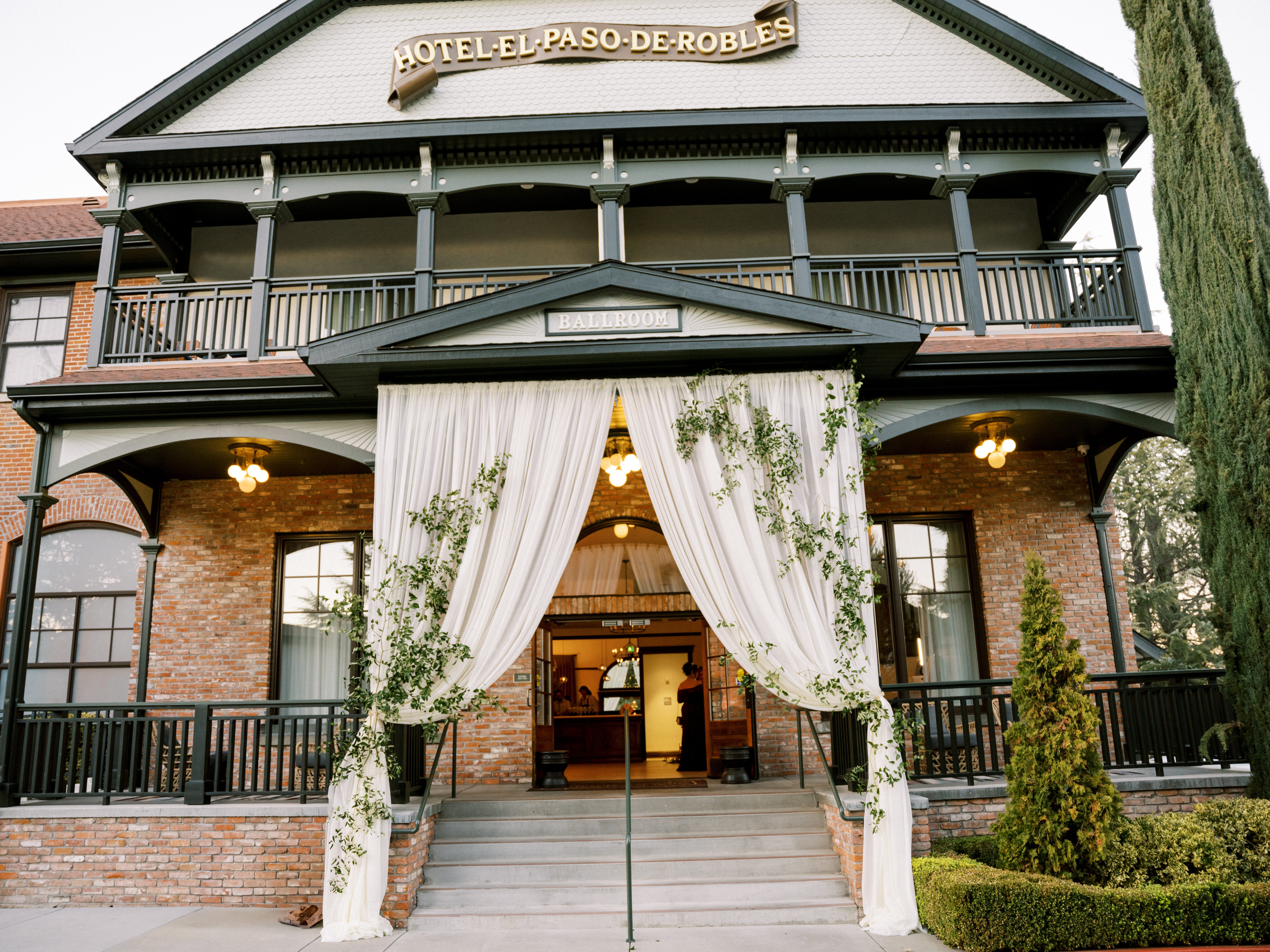 Exterior of Hotel El Paso de Robles decorated with draping and greenery for a Regency-inspired Central Coast wedding event
