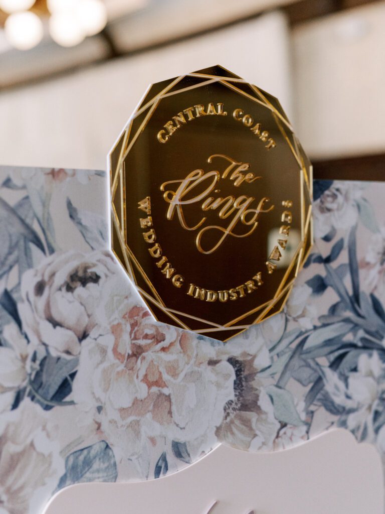 The Rings Awards crest signage with floral backdrop