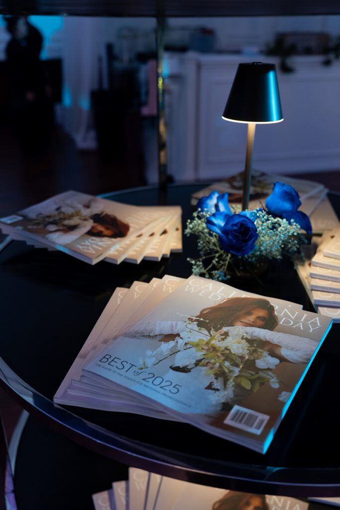 California Wedding Day Best of 2025 magazine display at awards gala event with styled blue lighting and florals.