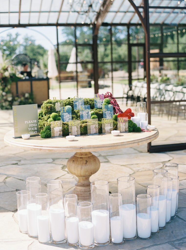 Modern wedding seating chart with custom acrylic escort cards displayed in moss and surrounded by candles