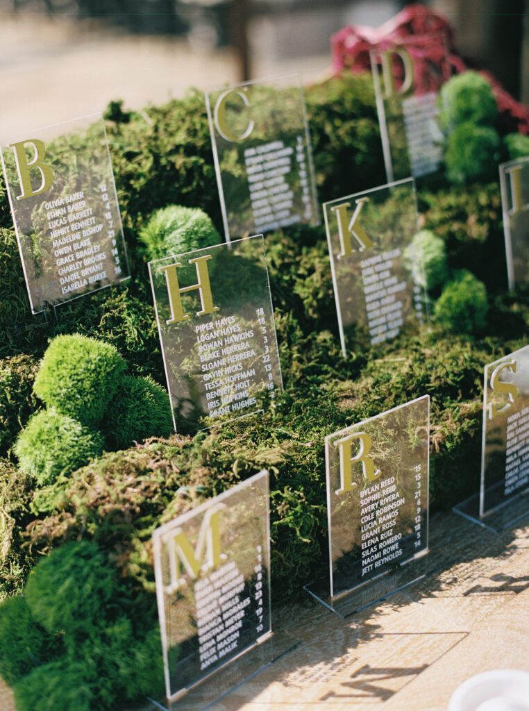 Custom acrylic wedding seating cards layered throughout a green moss installation at Riata Ranch