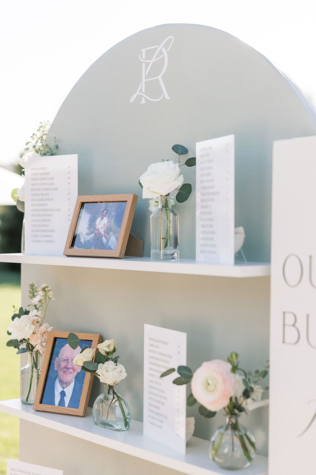 Sage wedding seating display with guest assignments, flowers and family photographs